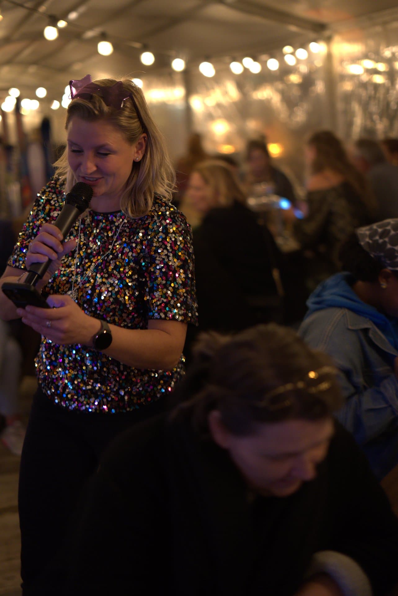 Pubquiz voor bedrijven publiek wordt toegesproken Quizmaster in feestelijke outfit spreekt het publiek toe tijdens een pubquiz voor bedrijven, omringd door sfeervolle zaalverlichting.