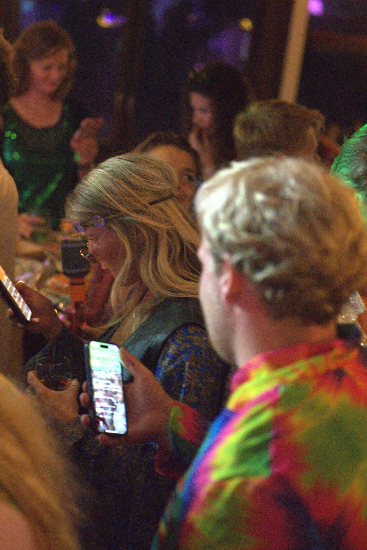 Pubquiz voor bedrijven ontspannen sfeerbeeld Sfeerbeeld van een pubquiz voor bedrijven waar gasten in feestelijke kleding ontspannen bijpraten en hun antwoorden op de telefoon invoeren.