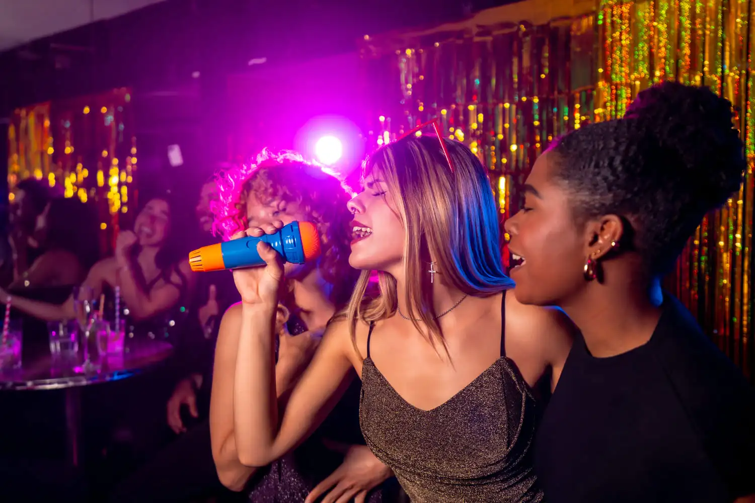Jonge vrouw zingt met een kleurrijke microfoon op een levendig discofeest tijdens Crazy Disco Bingo, omringd door feestelijke verlichting en een glinsterend goudkleurig gordijn.
