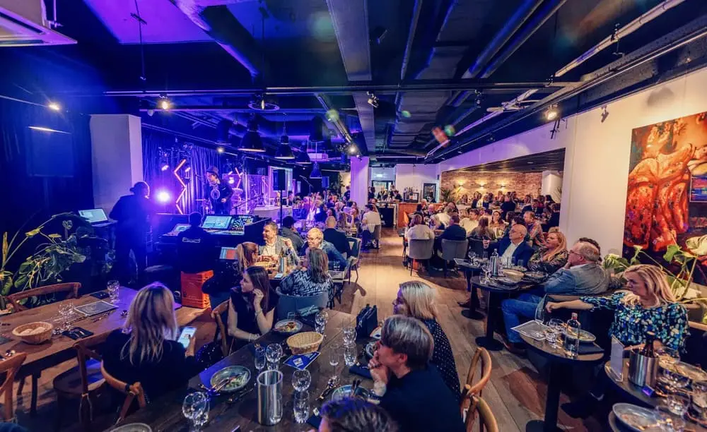 Gezellige pubquizavond in een sfeervol restaurant met mensen die genieten van eten, drinken en een live optreden.