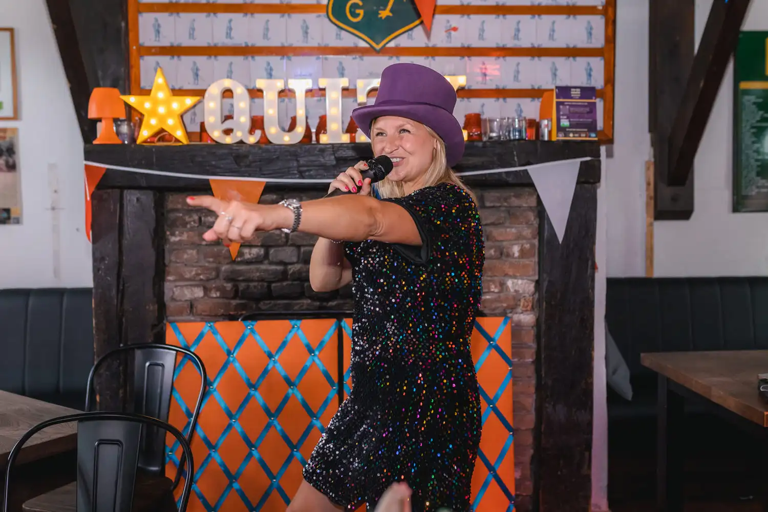 Enthousiaste vrouw leidt de 'Ik hou van Holland' quiz in kleurrijke setting met feestelijke versiering.