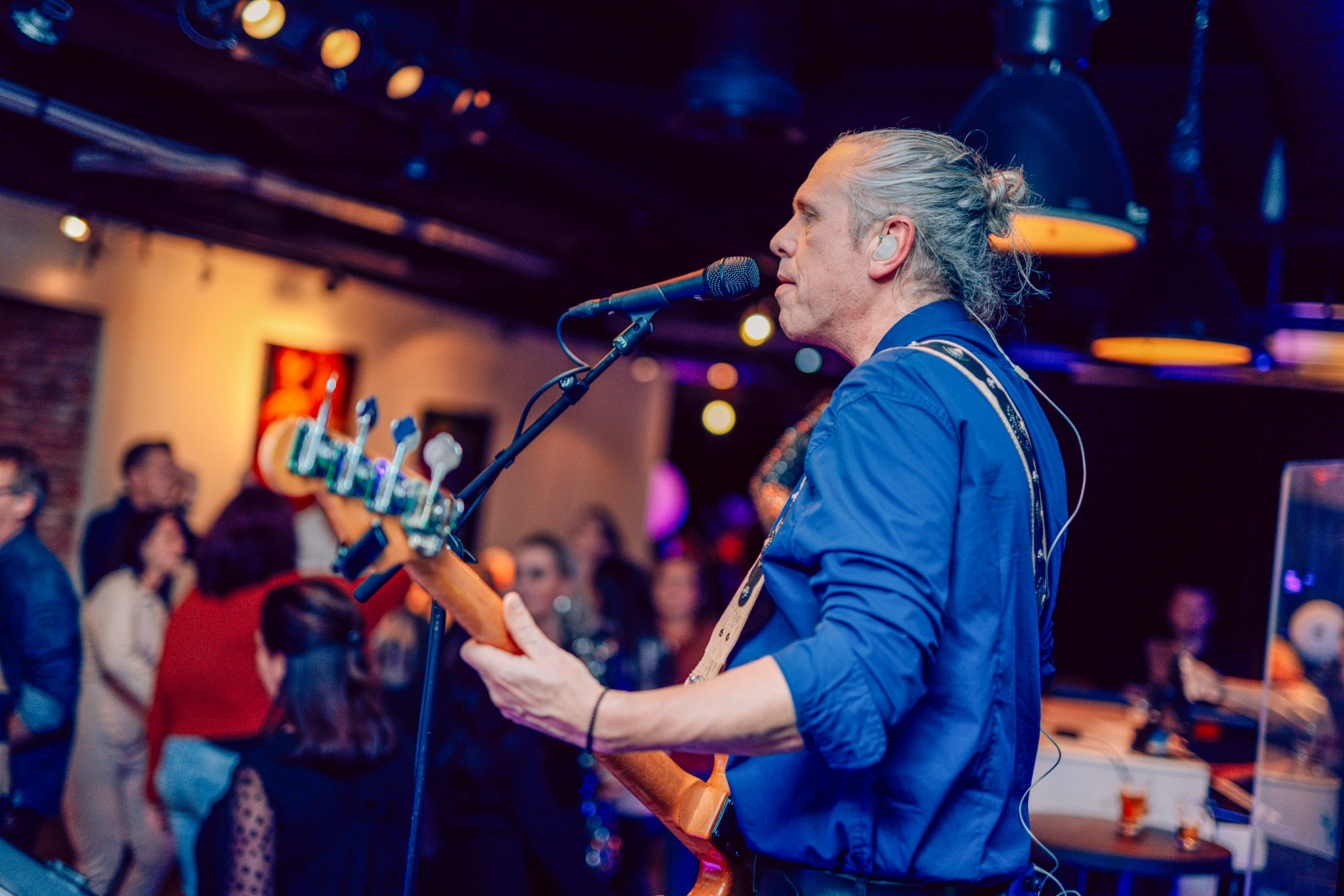 Muzikant speelt basgitaar tijdens live optreden voor een publiek in Den Haag's pubquiz.
