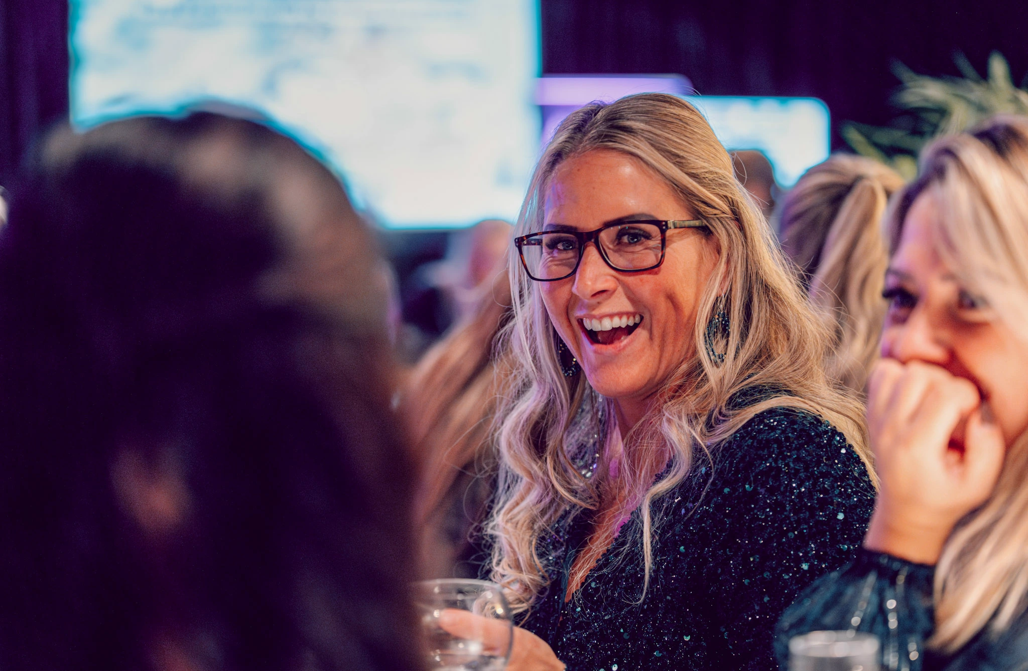 Groep mensen die genieten van een avondje uit tijdens een pubquiz in Den Haag, met een lachende vrouw op de voorgrond.