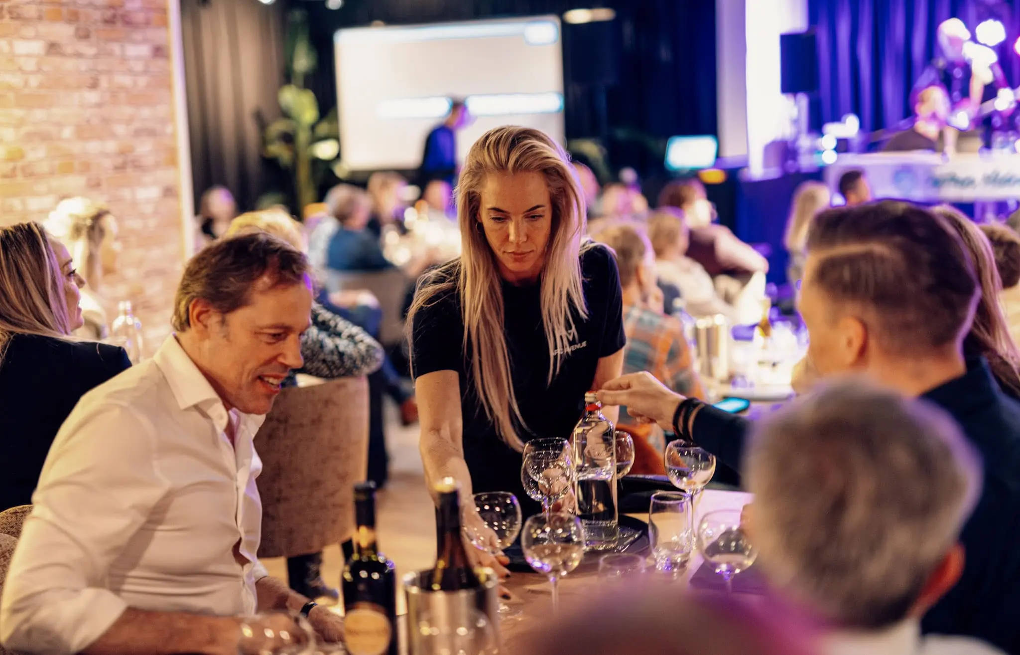 Gezellige sfeer tijdens een evenement met een gastvrouw die drankjes serveert, ideaal voor een quizmaster inhuren.