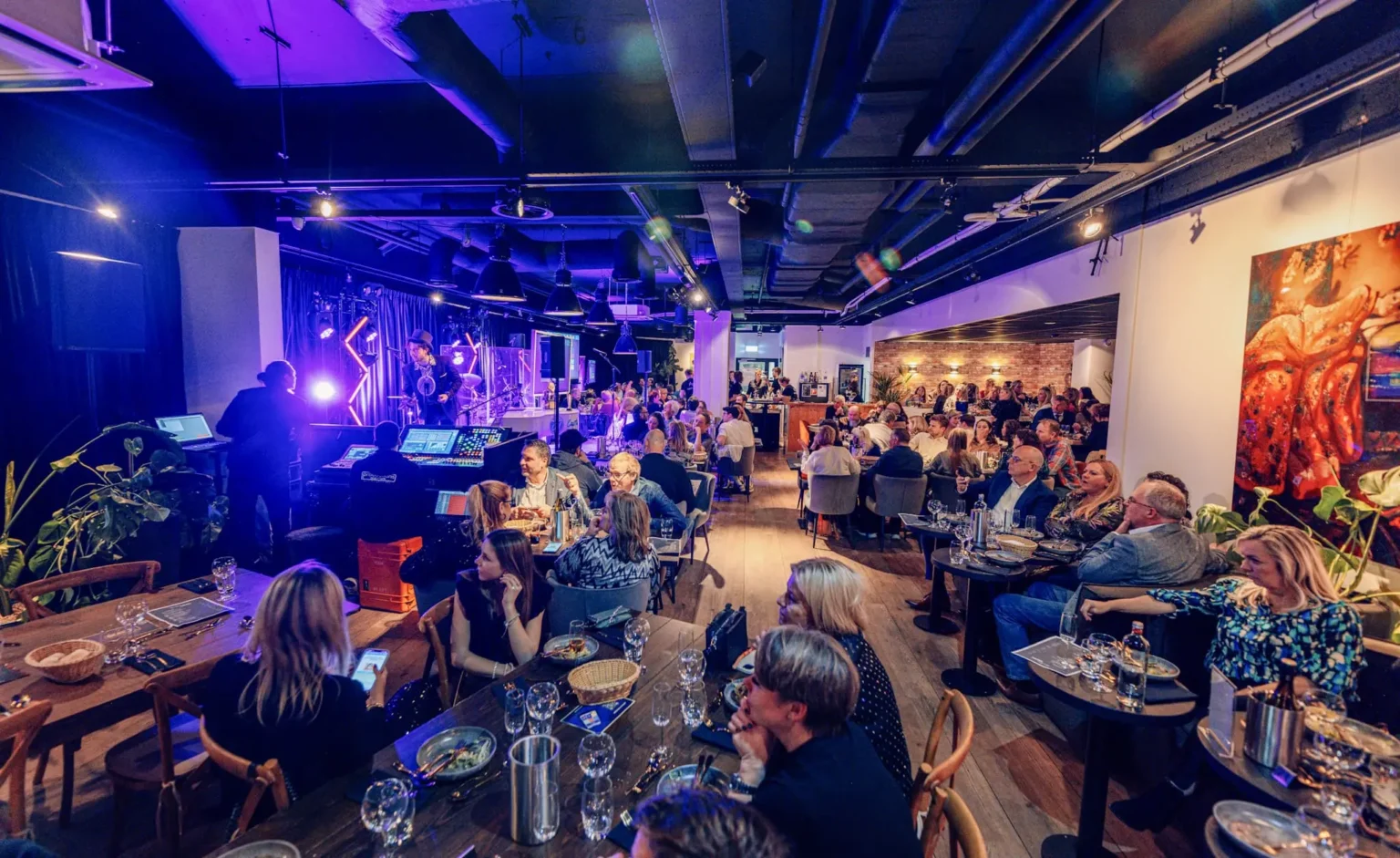 Drukke quizavond in een restaurant met felgekleurde lichten en een podium, waar gasten ontspannen genieten. Quizmaster inhuren voor evenementen binnen.