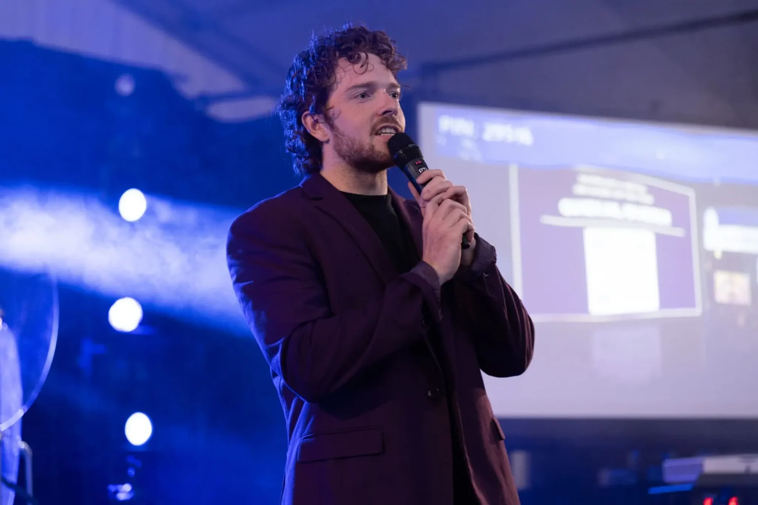 Professionele quizmaster op podium tijdens interactieve evenementpresentatie. Quizmaster inhuren voor quizavonden.