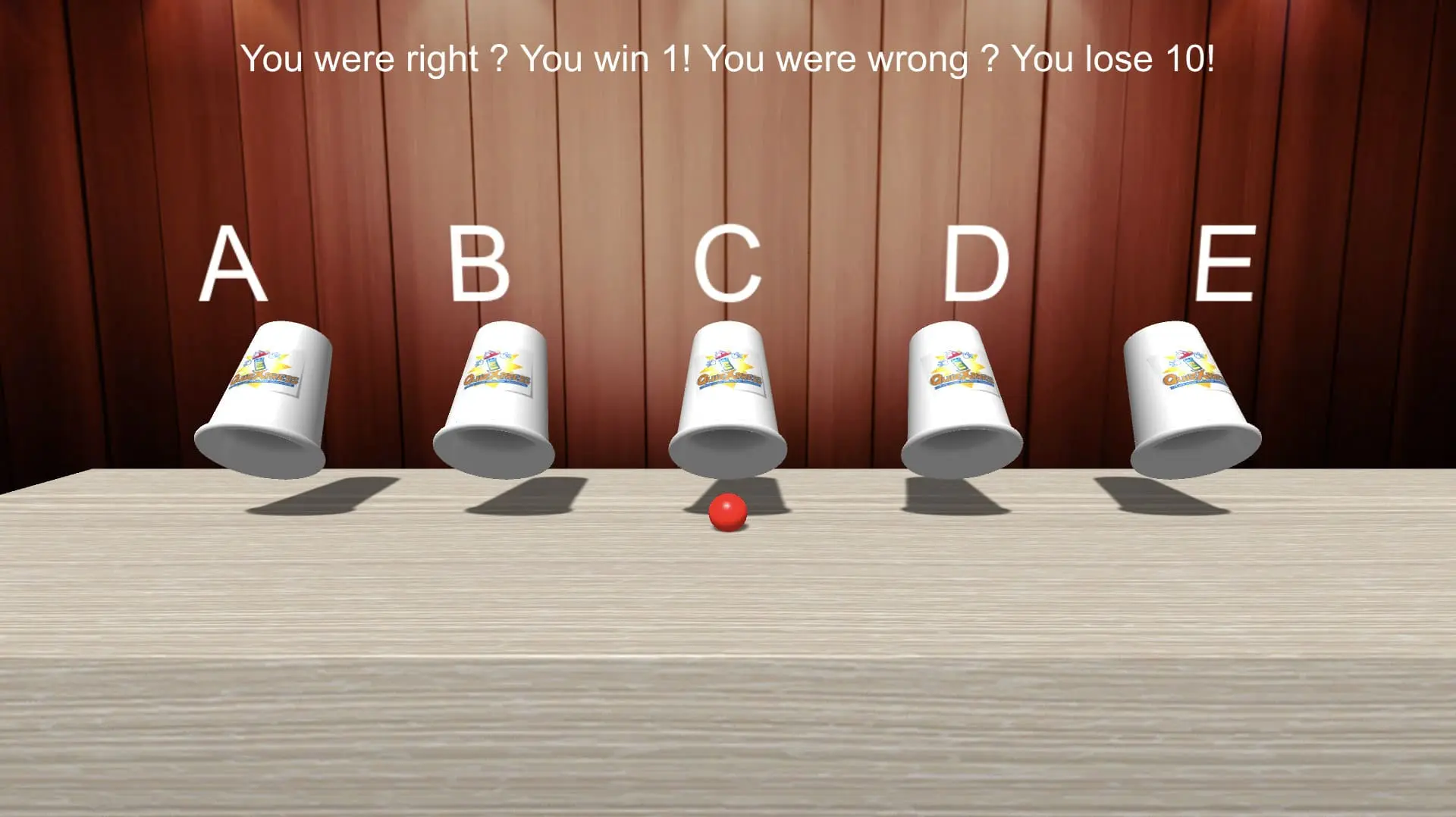 Afbeelding van bekerspel met vijf gemarkeerde bekers en een rode bal, gebruikt in quizvragen en pubquiz context van QuizX.